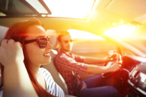 Houston Holiday Traffic Guide | Car Safety & Maintenance Tips | Sherwood Forest Auto Specialists. Image of man and woman driving in car with sunglasses on.
